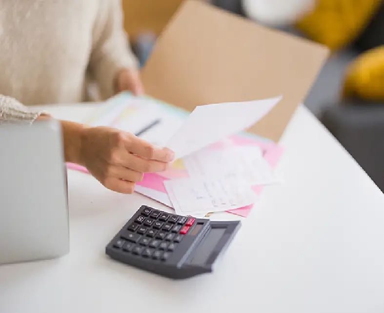 Person reviewing financial documents with a calculator on the desk.